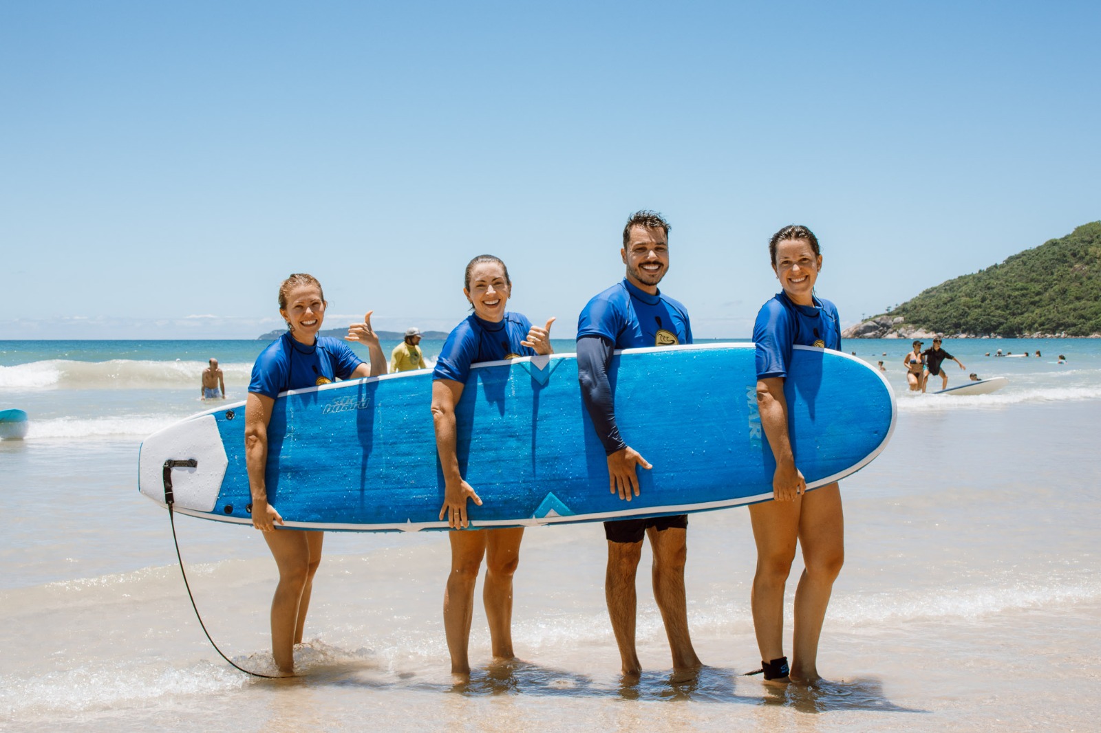 Turma de alunos sorrindo na praia
